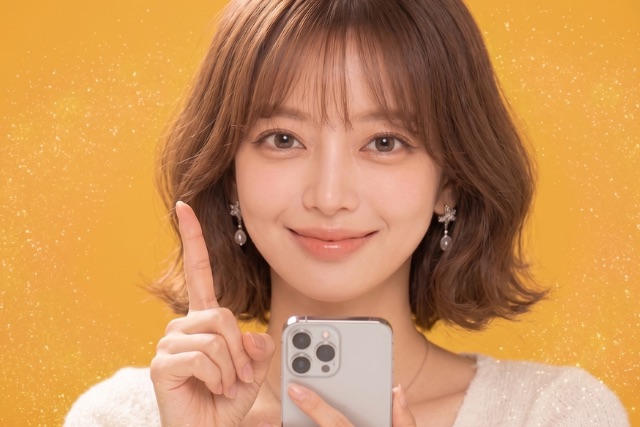 スマホを持って人差し指を立てる女性