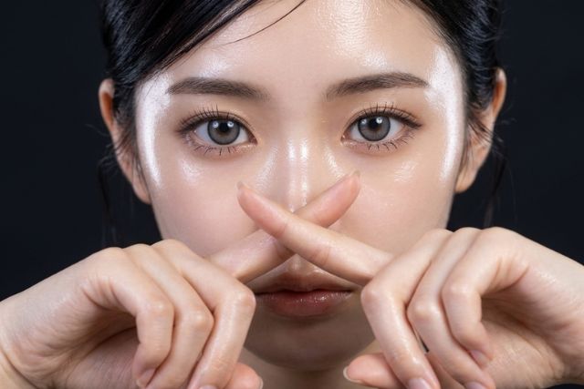 顔の前で人差し指をクロスする若い女性