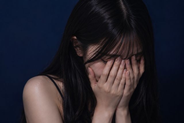 顔を手で覆う若い女性