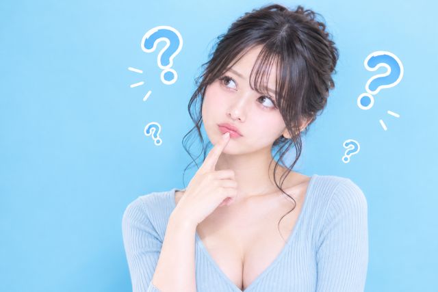 人差し指を口に当てて首を傾げ、斜め上を見る女の子