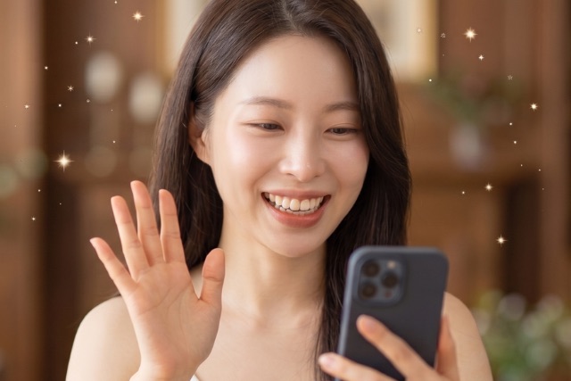 スマホに向かって手を振る女性