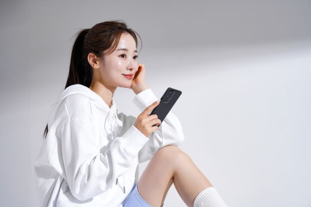 携帯を持ちながら何かを考える女性