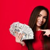 赤い背景の前でお札を持つ女性