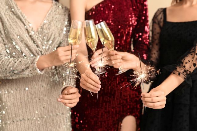 シャンパンで乾杯する3人のドレスの女性