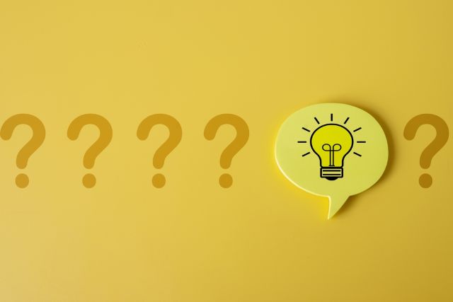 黄色の背景の前にあるハテナマークと電球のマーク