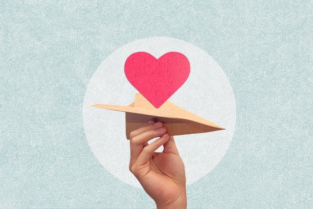 女性が持つ紙飛行機に載っているハートマーク