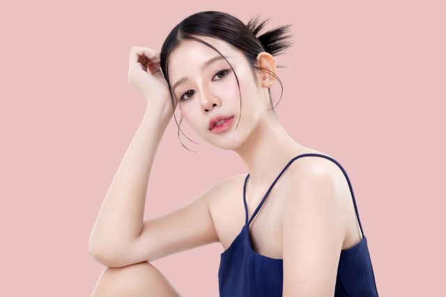 ピンクの背景のまえでポーズをとる女性