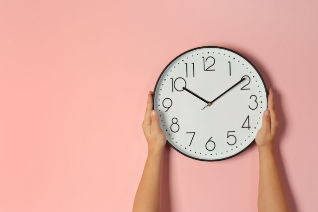 ピンクの背景の前にある時計