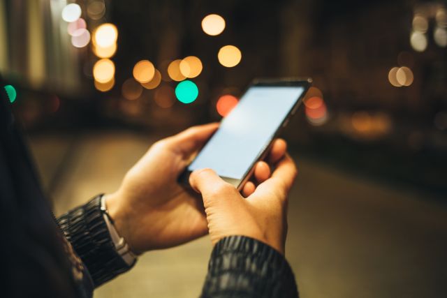 夜の道で携帯を触る女性の手