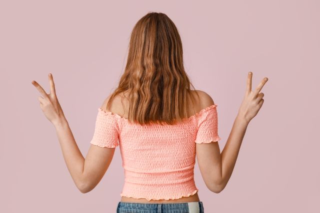 ピースをする後ろ姿の女性