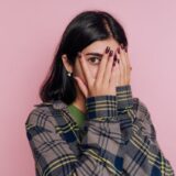 顔を隠して片目でこちらを見る女性