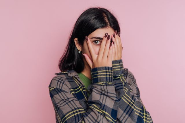 顔を隠して片目でこちらを見る女性