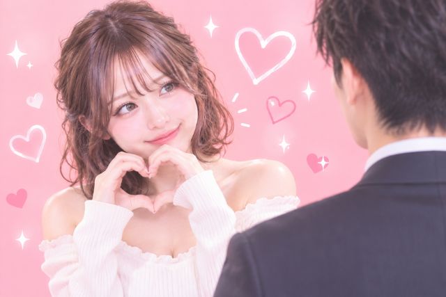 ゆるふわボブの女性がハートを作って隣の男性の方を見ている