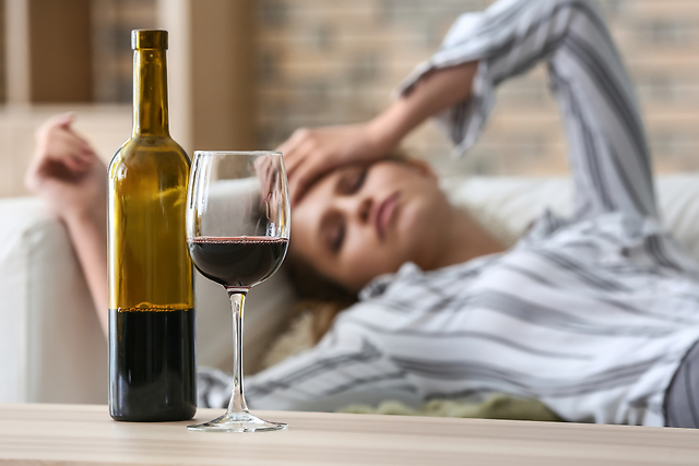 ワインを飲んでソファに寝転ぶ女性
