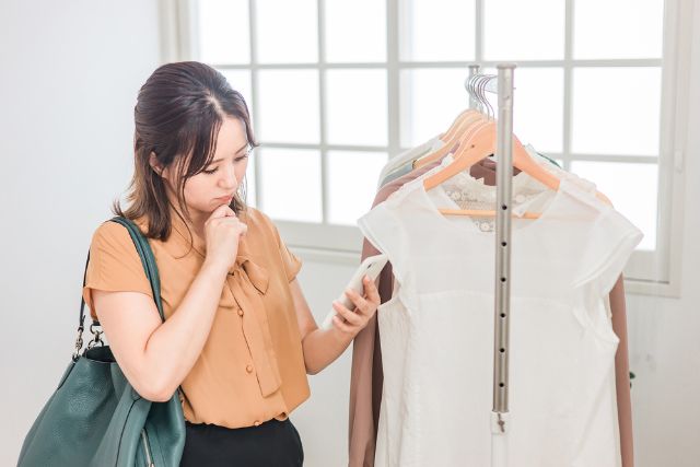 スマホを見ながらどんな服が良いか悩む女性