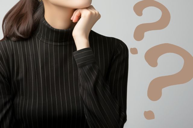 黒い服を着た女性があごに手を当て疑問を感じている様子