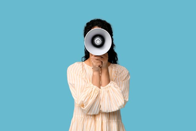 顔の前にメガホンを持つ女性