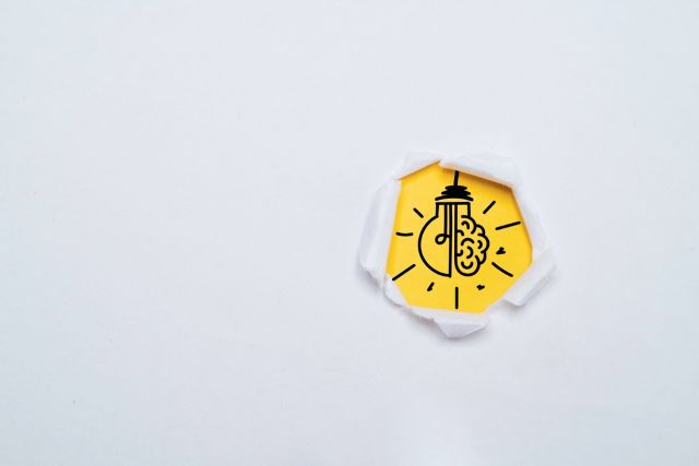 破れた背景から出る電球と脳のマーク